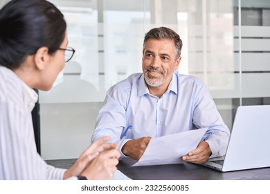 Smiling professional Latin employer hr manager holding cv during interview hiring for job female Asian female recruit, advisor consulting client sitting in office at meeting. Human resources. - Powered by Shutterstock