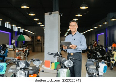 smiling professional salesman standing and holding tablet in electric bike showroom - Powered by Shutterstock