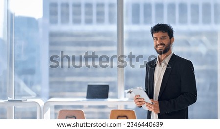 Smiling professional young latin business man company employee, male corporate manager office worker looking at camera holding digital tablet standing in office with big windows, portrait, copy space.