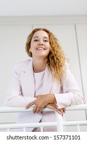 Smiling Proud Business Woman Standing In Office Hallway Leaning On Railing Shot From Below