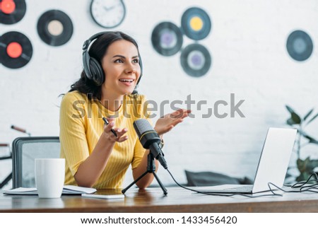 smiling radio host gesturing while recording podcast in broadcasting studio