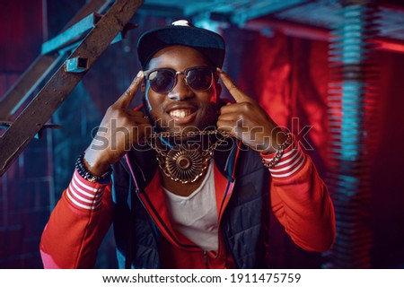Smiling rapper with gold chain posing in studio