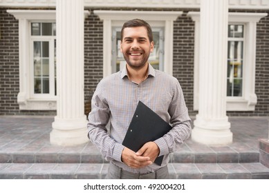 Smiling Realtor Standing Outside Modern House