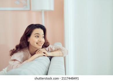 Smiling Relaxed Attractive Woman Wearing Glasses Sitting On A Sofa Looking Back Over Her Shoulder 