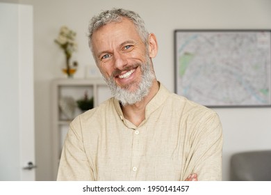 Smiling relaxed mature older bearded hipster man looking at camera. Happy handsome confident middle aged 50s male professional, standing at home office posing indoors for close up headshot portrait. - Shutterstock ID 1950141457