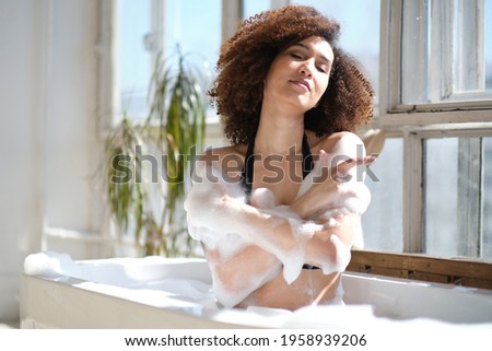 Smiling and relaxing african american woman bathing in a tub full of foam. Amazing time. lifestyle people concept