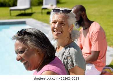 Smiling and relaxing by pool, diverse group of senior friends enjoying sunny day. Seniors, relaxation, friendship, outdoor, leisure, summer, fun, vacation, unaltered - Powered by Shutterstock