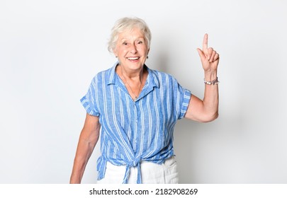 A Smiling Retired Senior Woman Looking At Camera Isolated On White Background Pointing Something