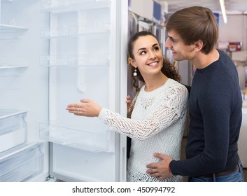 Smiling Russian Family Couple Choosing New Refrigerator In Hypermarket 