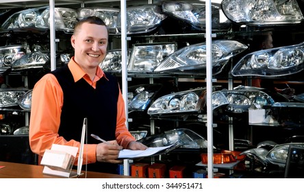 Smiling Salesman Auto Parts Store With A Notebook In Hand