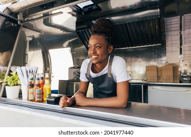 Smiling saleswoman in apron leaning counter standing in a food truck - Powered by Shutterstock