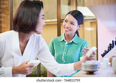 Smiling Saleswoman Helping Young Woman To Choose Cosmetics In The Store