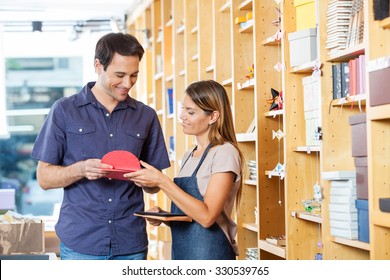 Smiling saleswoman showing greeting cards to male customer in shop