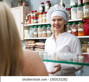 Smiling Satisfied Mature Woman Buying Different Nuts In Local Confectionery