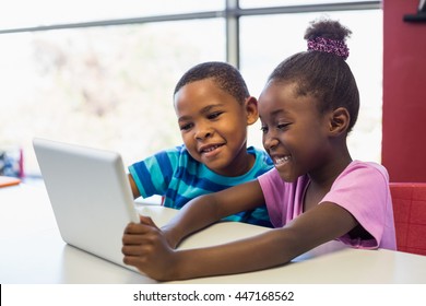 Smiling school kids using a digital tablet in classroom at school