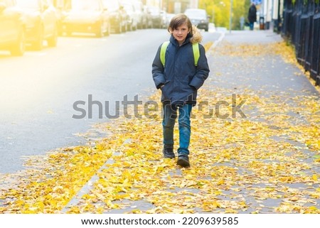 a smiling schoolboy with a backpack outside