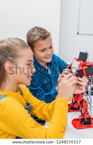 smiling schoolchildren programming robot together during STEM educational class