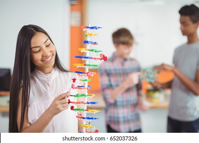 Smiling schoolgirl studying molecule model in laboratory at school - Powered by Shutterstock