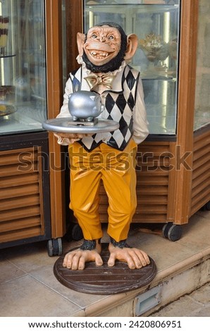 Smiling sculpture of a monkey in a suit with a tray in his hand