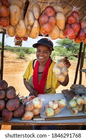 smiling self employed african woman at her street stall selling fresh  vegetables