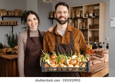 Smiling Sellers Man And Woman Holding Basket With Onion While Working In Local Eco Shop