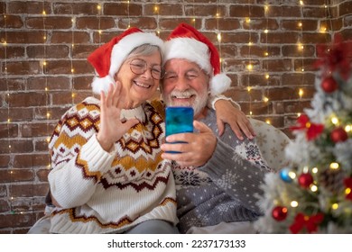 Smiling senior adult couple sitting at home at Christmas time in video call with family or friends. Lovely elderly man and woman stay together at celebration event - Powered by Shutterstock