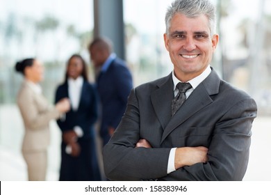 Smiling Senior Business Executive With Arms Folded In Office