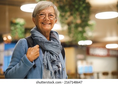 Smiling Senior Caucasian Traveler Woman With Backpack At The Airport Gate Waiting For Departure Flight