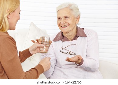 Smiling Senior Citizen Woman Taking Medical Pill With A Cup Of Water