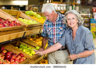 Smiling senior couple buying apples at the grocery shop - Powered by Shutterstock