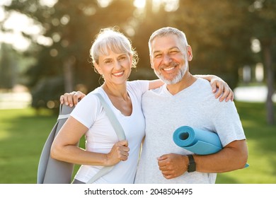Smiling senior couple with exercise mats standing at park, positive mature man embracing his elderly wife after fitness or yoga class in nature. Wellness and healthy lifestyle on retirement - Powered by Shutterstock