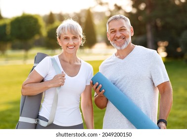 Smiling senior couple with exercise mats standing at park, positive mature man embracing his elderly wife after fitness or yoga class in nature. Wellness and healthy lifestyle on retirement - Powered by Shutterstock