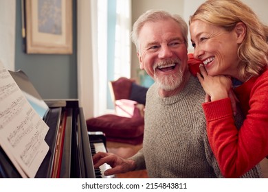 Smiling Senior Couple At Home Enjoying Learning To Play Piano - Powered by Shutterstock