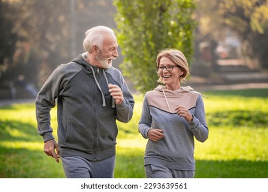 Smiling senior couple jogging in the park. Sports activities for elderly people - Powered by Shutterstock