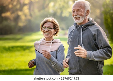 Smiling senior couple jogging in the park. Sports activities for elderly people - Powered by Shutterstock