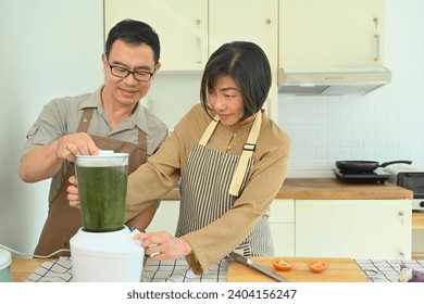 Smiling senior couple making healthy smoothie with blender in kitchen. Healthy lifestyle and dieting concept. - Powered by Shutterstock