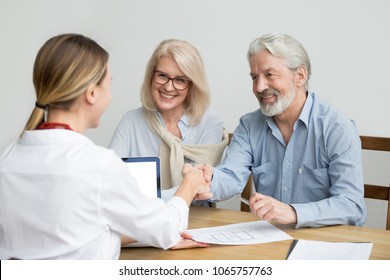 Smiling Senior Couple And Realtor Handshaking Making Real Estate Deal, Older Man And Mortgage Broker Shaking Hands, Aged Family Buyers Agree To Make Investment Or Purchase New House At Meeting