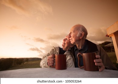 Smiling Senior Couple Sitting Outside At Sunset