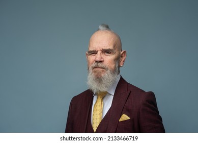 Smiling Senior Elegant Man In A Purple Suit And A Yellow Tie Standing Against The Blue Background In A Studio