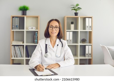 Smiling Senior Female Doctor Taking Notes During Video Conference With Colleagues Or Listening To Online Medical Training. Concept Of Online Training For Doctors And Modern Technology. Webcam View.