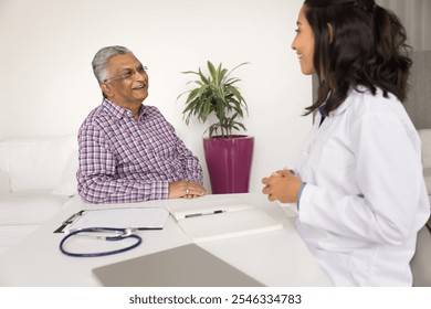 Smiling senior Indian man talking to young Brazilian woman cardiologist during visit in clinic, receive good news about effective treatment of disease, get professional medical services feel satisfied - Powered by Shutterstock