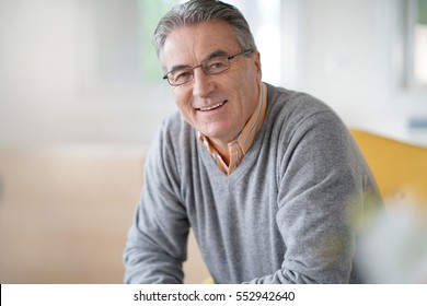 Smiling senior man with eyeglasses relaxing in armchair - Shutterstock ID 552942640