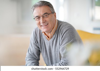 Smiling senior man with eyeglasses relaxing in armchair - Shutterstock ID 552964729
