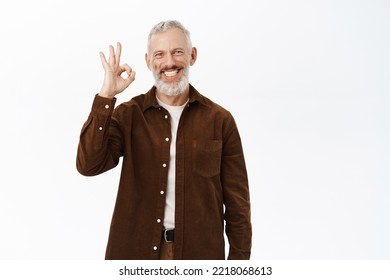 Smiling Senior Man, Mature Male Model Showing Okay Sign, Praise And Compliment, Recommending Smth Awesome, Standing Over White Background