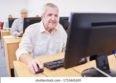 Un anciano sonriente aprende el uso de Internet en un curso de informática