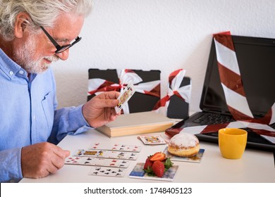 Smiling Senior Man Says Stop Technology In Favor Of A Game Of Cards, No More Web Addiction. Stop Internet For Tablet Computer And Mobile Phone. Defocused Devices, Focus On Man