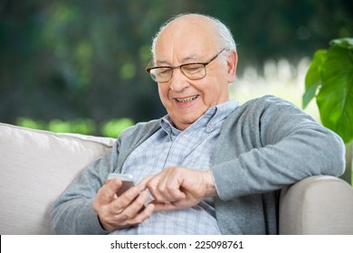 Smiling senior man text messaging through mobile phone at nursing home porch - Powered by Shutterstock