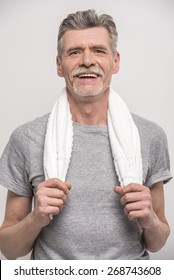 Smiling Senior Man In T-shirt On Neck Towel On Grey Background.