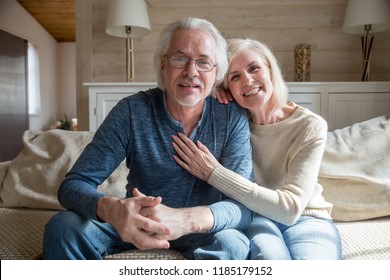 Smiling Senior Middle Aged Vloggers Couple Looking Talking At Camera Recording Video Blog At Home, Happy Friendly Mature Old Family Making Videocall Sitting On Sofa, Elderly Lifestyle Vlog Concept