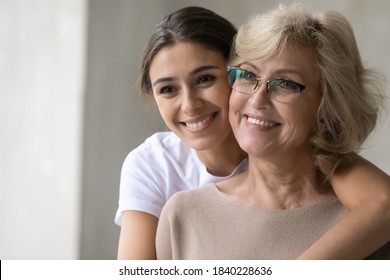 Smiling Senior Mother And Adult Daughter Hug Cuddle Look In Distance Dream Think Of Happy Future. Optimistic Mature Mom And Grownup Girl Child Embrace Visualize At Home, Enjoy Tender Family Moment.